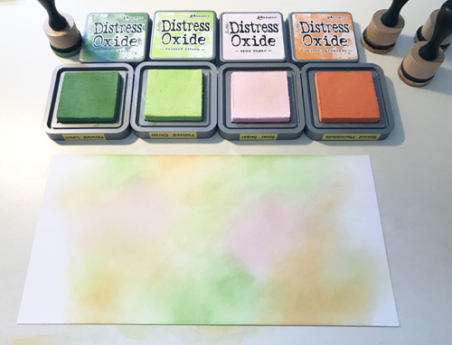 Create a watercolor background with Distress Oxide inks by Ranger Ink and Tim Holtz. 